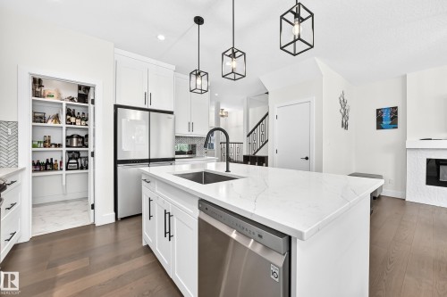 Bright kitchen featuring a substantial island with a built-in sink and stainless steel dishwasher - 22270 99A Avenue Nw, Edmonton, AB - Indoor Photo Showing Kitchen With Upgraded Kitchen