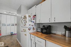 Kitchen area featuring white cabinetry, a wood-finish countertop, and a white subway tile backsplash - 