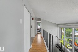 Hallway featuring wood-finish flooring, light gray wall paint, and white trim - 