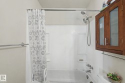 White tub and shower combination with a wall-mounted shower system - 