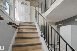 Wood-finish staircase with dark treads and a black metal railing - 