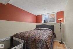 Bedroom featuring a window with white trim, wood-finish flooring, and a two-tone painted wall - 