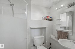 Bathroom featuring a frosted glass shower enclosure, white toilet, and pedestal sink - 