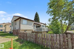 Rear exterior featuring siding, a white railing deck, and mature trees - 