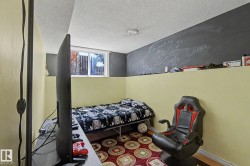 Room featuring wood-finish flooring, a neutral wall color, and a partial dark accent wall with a chalkboard finish - 