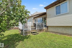 Expansive rear yard featuring a wooden deck with white railings, a partial fence, and mature trees - 