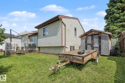 Expansive backyard featuring a wood deck with white railings, a sliding glass door entry, and a dedicated storage shed - 