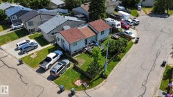Corner lot residence featuring a light-colored exterior and a multi-gabled roofline with reddish-brown shingles - 