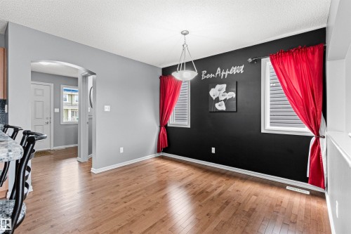 Dining area featuring wood-finish flooring, a contemporary ceiling light fixture, and two windows with horizontal blinds - 1154 35A Avenue Nw, Edmonton, AB - Indoor Photo Showing Other Room