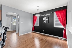 Dining area featuring wood-finish flooring, a contemporary ceiling light fixture, and two windows with horizontal blinds - 