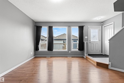 Open-concept living area with wood-finish flooring, light gray walls, and white trim - 1154 35A Avenue Nw, Edmonton, AB - Indoor Photo Showing Other Room