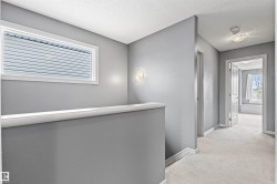 Carpeted hallway featuring a rectangular window with horizontal blinds, a wall sconce, and white trim - 