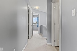 Upper-level hallway with light gray walls, white trim, and light-colored carpet flooring - 