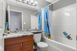 Bathroom featuring a wood-finish vanity with a granite-style countertop, undermount sink, and chrome faucet - 