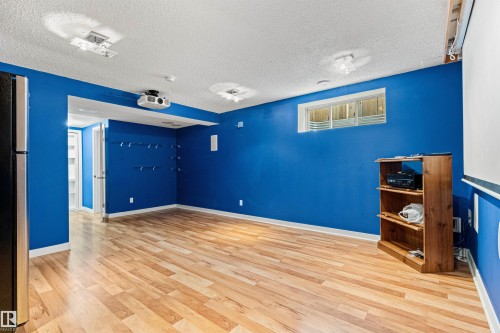 Finished lower level featuring recessed lighting, wood-finish flooring, a wall-mounted projector, and a window well - 1154 35A Avenue Nw, Edmonton, AB - Indoor Photo Showing Other Room