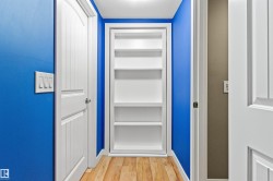 Hallway featuring built-in shelving, paneled interior doors, light wood-finish flooring, and bright wall finishes - 