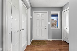 Entryway featuring a white paneled front door, wood-finish flooring, a rectangular window, and two closet doors - 