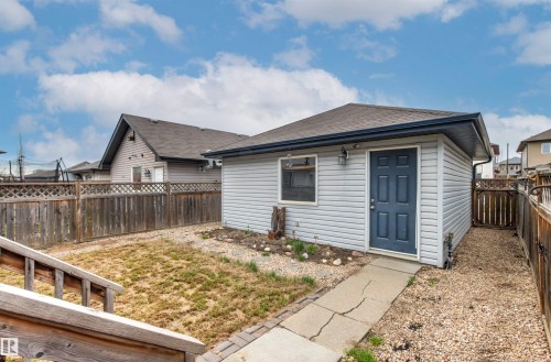 Detached accessory building featuring light gray siding, a dark blue entry door, and a single window - 1154 35A Avenue Nw, Edmonton, AB - Outdoor With Exterior