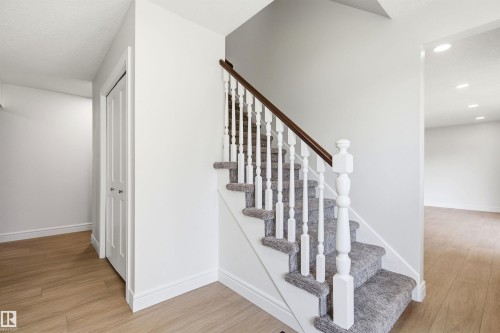 Staircase featuring a dark wood handrail, white balusters, and carpeted treads - 14335 47 Avenue Nw, Edmonton, AB - Indoor Photo Showing Other Room