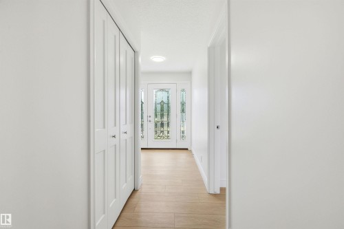 Entryway featuring wood-finish flooring, white bifold closet doors, recessed lighting, and a front door with decorative glass inserts - 14335 47 Avenue Nw, Edmonton, AB - Indoor Photo Showing Other Room
