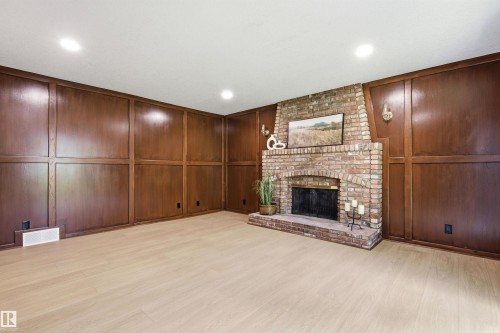 Brick-surround fireplace with a hearth, flanked by symmetrical wood paneling - 14335 47 Avenue Nw, Edmonton, AB - Indoor With Fireplace