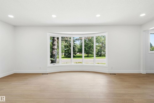 Spacious room featuring a prominent bay window with white trim, light wood-finish flooring, recessed lighting, and white baseboards - 14335 47 Avenue Nw, Edmonton, AB - Indoor Photo Showing Other Room