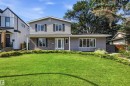Two-story residence featuring gray siding with dark shutters, a stone façade, and a vibrant green lawn - 14335 47 Avenue Nw, Edmonton, AB  - Outdoor With Facade 