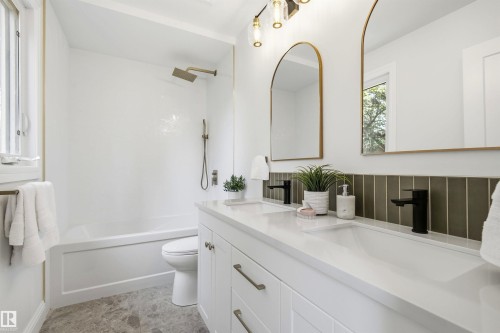 Bathroom featuring a double vanity with integrated sinks, black finish faucets, and a dark green subway tile backsplash - 14335 47 Avenue Nw, Edmonton, AB - Indoor Photo Showing Bathroom