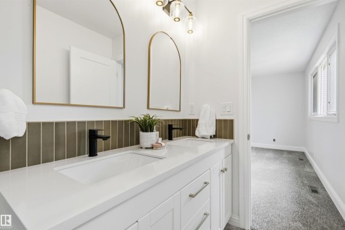 Double vanity with integrated sinks, white countertop, and matte black faucets - 14335 47 Avenue Nw, Edmonton, AB - Indoor Photo Showing Bathroom