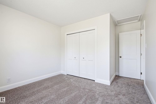 Neutral wall colors, plush carpet flooring, white baseboards, white bi-fold closet doors, and white interior door - 14335 47 Avenue Nw, Edmonton, AB - Indoor Photo Showing Other Room