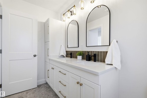 Double vanity featuring white cabinetry, brass hardware, and white countertops - 14335 47 Avenue Nw, Edmonton, AB - Indoor Photo Showing Other Room