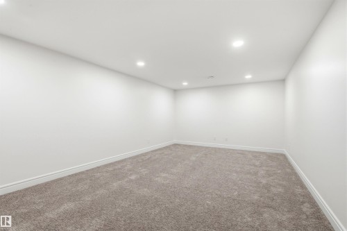 Spacious room featuring neutral carpeting, white walls, recessed ceiling lighting, and crisp white baseboards - 14335 47 Avenue Nw, Edmonton, AB - Indoor Photo Showing Other Room