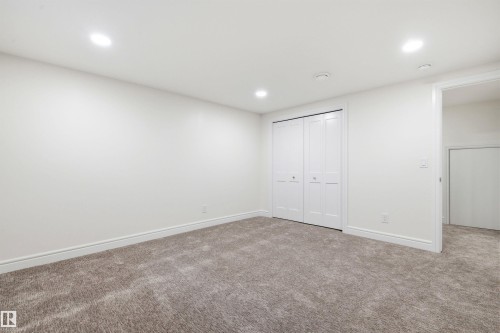 Carpeted room featuring white walls, recessed ceiling lighting, a bi-fold closet, and white baseboards - 14335 47 Avenue Nw, Edmonton, AB - Indoor Photo Showing Other Room