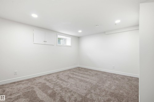 Spacious room featuring neutral carpeting, white painted walls, recessed lighting, a built-in cabinet, and a window with blinds - 14335 47 Avenue Nw, Edmonton, AB - Indoor Photo Showing Other Room