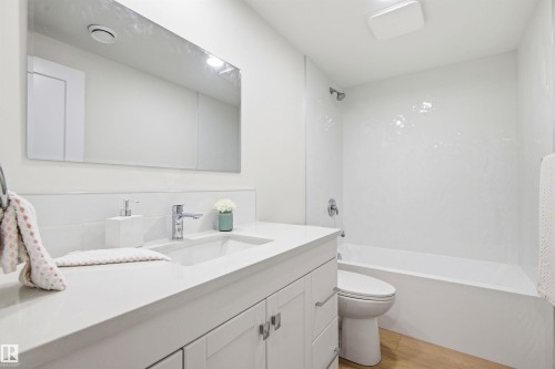 Bathroom featuring a white vanity with an integrated sink, chrome faucet, and a large wall-mounted mirror - 14335 47 Avenue Nw, Edmonton, AB - Indoor Photo Showing Bathroom