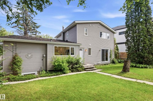 Spacious rear yard with a manicured lawn, established landscaping, and a concrete paver pathway - 14335 47 Avenue Nw, Edmonton, AB - Outdoor