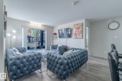 Living area featuring wood-finish flooring, light grey painted walls, and a sliding glass door providing natural light - 
