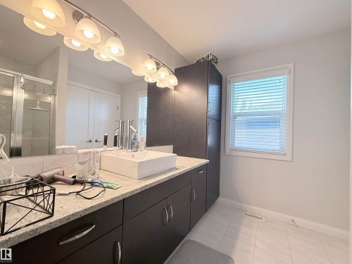 Modern bathroom featuring a double vanity with a rectangular vessel sink, granite-style countertop, and dark wood cabinetry - 5876 168 Avenue Nw, Edmonton, AB - Indoor Photo Showing Bathroom