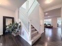 Bright entryway featuring dark wood-finish flooring, a carpeted staircase with frosted glass railing, and white trim throughout - 5876 168 Avenue Nw, Edmonton, AB  - Indoor Photo Showing Other Room 