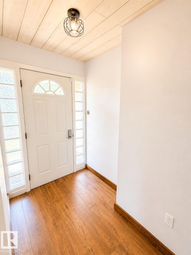 Entryway featuring a white door with an arched transom, sidelight windows, and wood-finish flooring - 610 8 Avenue, Wainwright, AB - Indoor Photo Showing Other Room