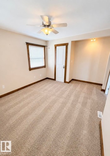 Carpeted room featuring a ceiling fan with integrated lighting, wood-trimmed window with blinds, a white paneled door with wood trim, and recessed lighting in an alcove - 610 8 Avenue, Wainwright, AB - Indoor Photo Showing Other Room