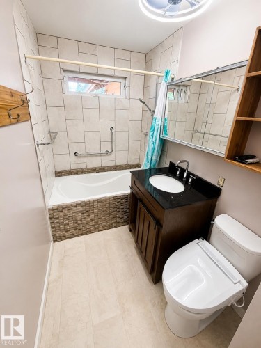Contemporary bathroom featuring a dark wood-finish vanity with a dark countertop, an integrated sink, and chrome fixtures - 610 8 Avenue, Wainwright, AB - Indoor Photo Showing Bathroom