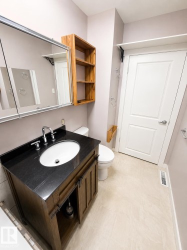 Bathroom featuring a dark wood-finish vanity with a black countertop, undermount sink, and chrome fixtures - 610 8 Avenue, Wainwright, AB - Indoor Photo Showing Bathroom