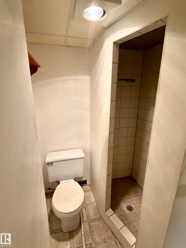 Compact bathroom featuring a white toilet, recessed ceiling lighting, and a tiled shower stall - 610 8 Avenue, Wainwright, AB - Indoor Photo Showing Bathroom