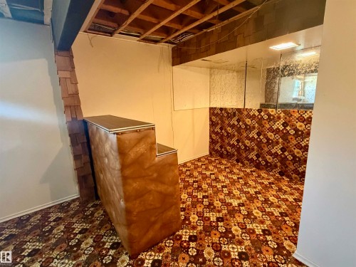 Room featuring patterned wall-to-wall carpeting, wood-paneled accents, and mirrored wall sections - 610 8 Avenue, Wainwright, AB - Indoor Photo Showing Basement