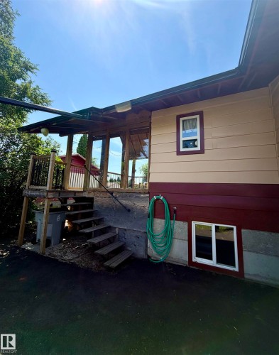 Exterior featuring a covered deck with wood posts and railing, multiple windows, and a lower-level window - 610 8 Avenue, Wainwright, AB - Outdoor