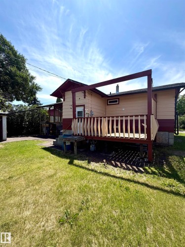 Rear exterior with a wood deck featuring a protective railing and an overhead framework - 610 8 Avenue, Wainwright, AB - Outdoor