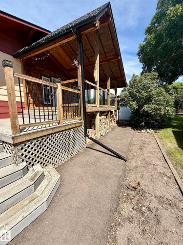 Wood-finish covered deck featuring a gabled roofline and black metal railings - 610 8 Avenue, Wainwright, AB - Outdoor