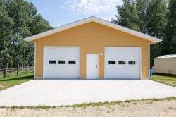 Two-car garage with yellow siding, white gable trim, and two paneled garage doors featuring rectangular windows - 