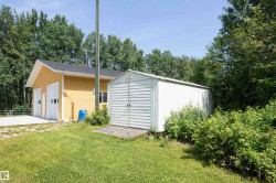 Detached garage building featuring a yellow siding exterior and two overhead garage doors with window inserts - 